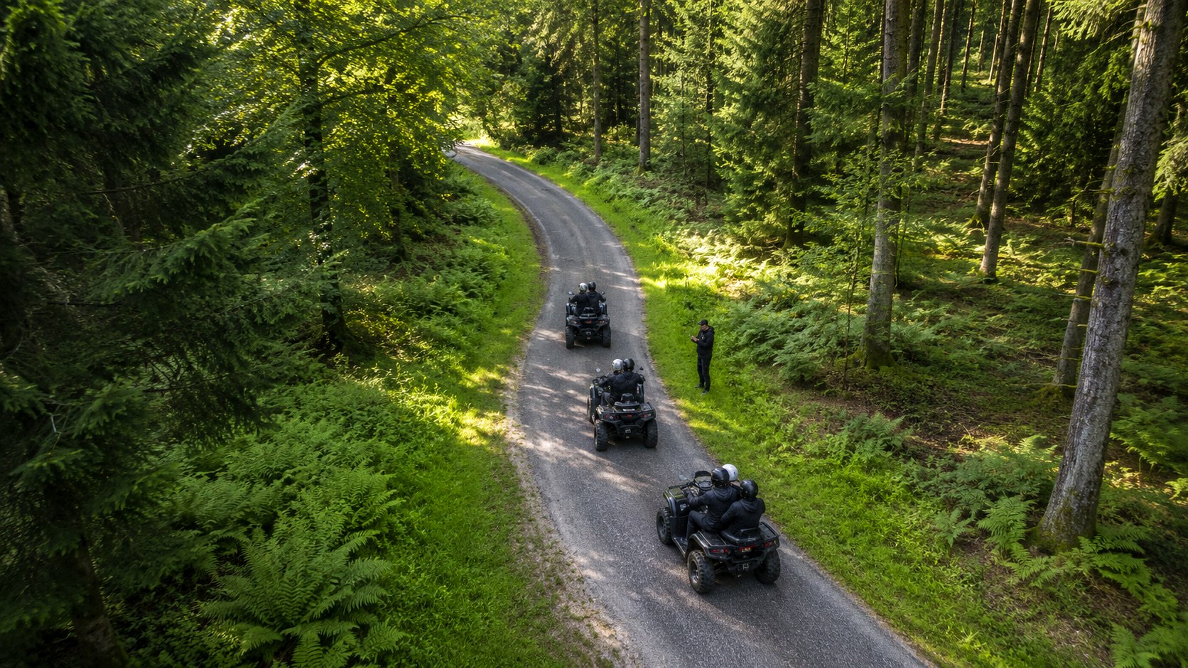 Vue d'un convoi de quads sur une route sinueuse en forêt